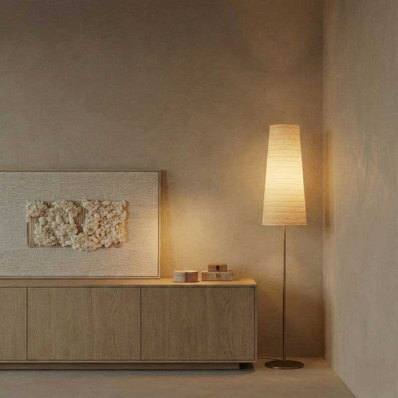 Modern interior with a wooden cabinet, textured wall art, and a floor lamp casting a warm glow.